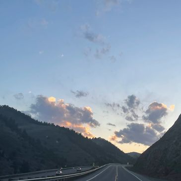 Empty highway winding through mountainous terrain at sunset.
