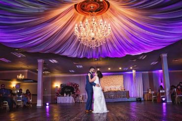 A couple dancing under a chandelier at a wedding reception.