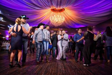 Couples dancing at a lively party under a colorful, draped ceiling.