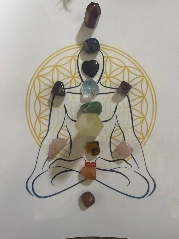 Colored crystals arranged on a meditative figure with a geometric circle background.