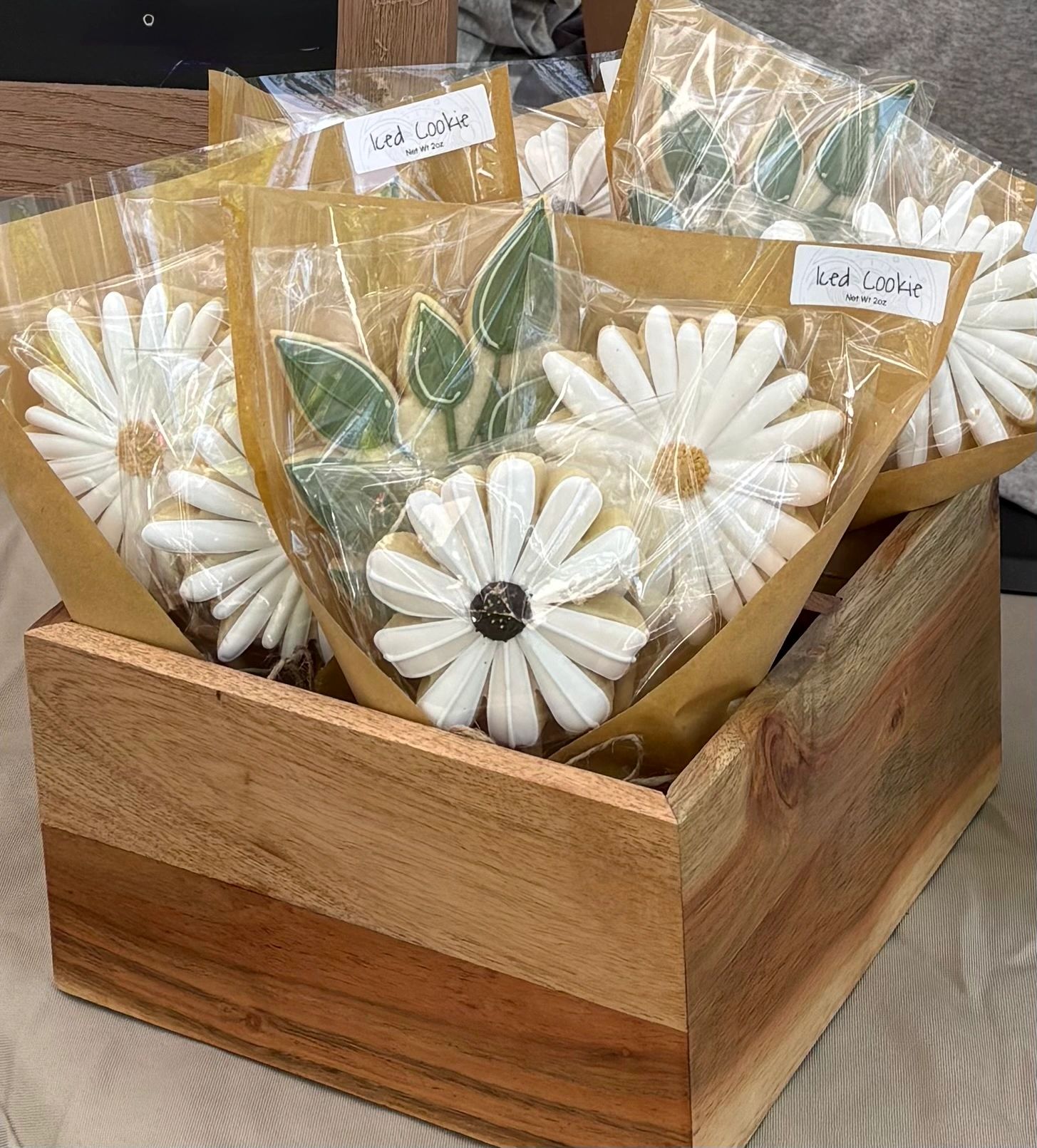 Flower-shaped iced cookies in a wooden box.