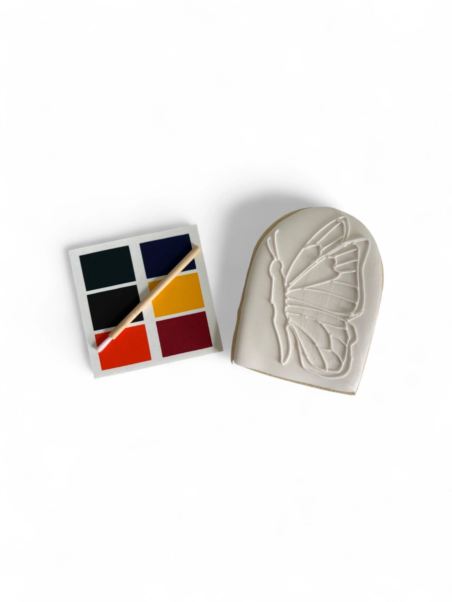 Color palette and butterfly art piece on white surface.