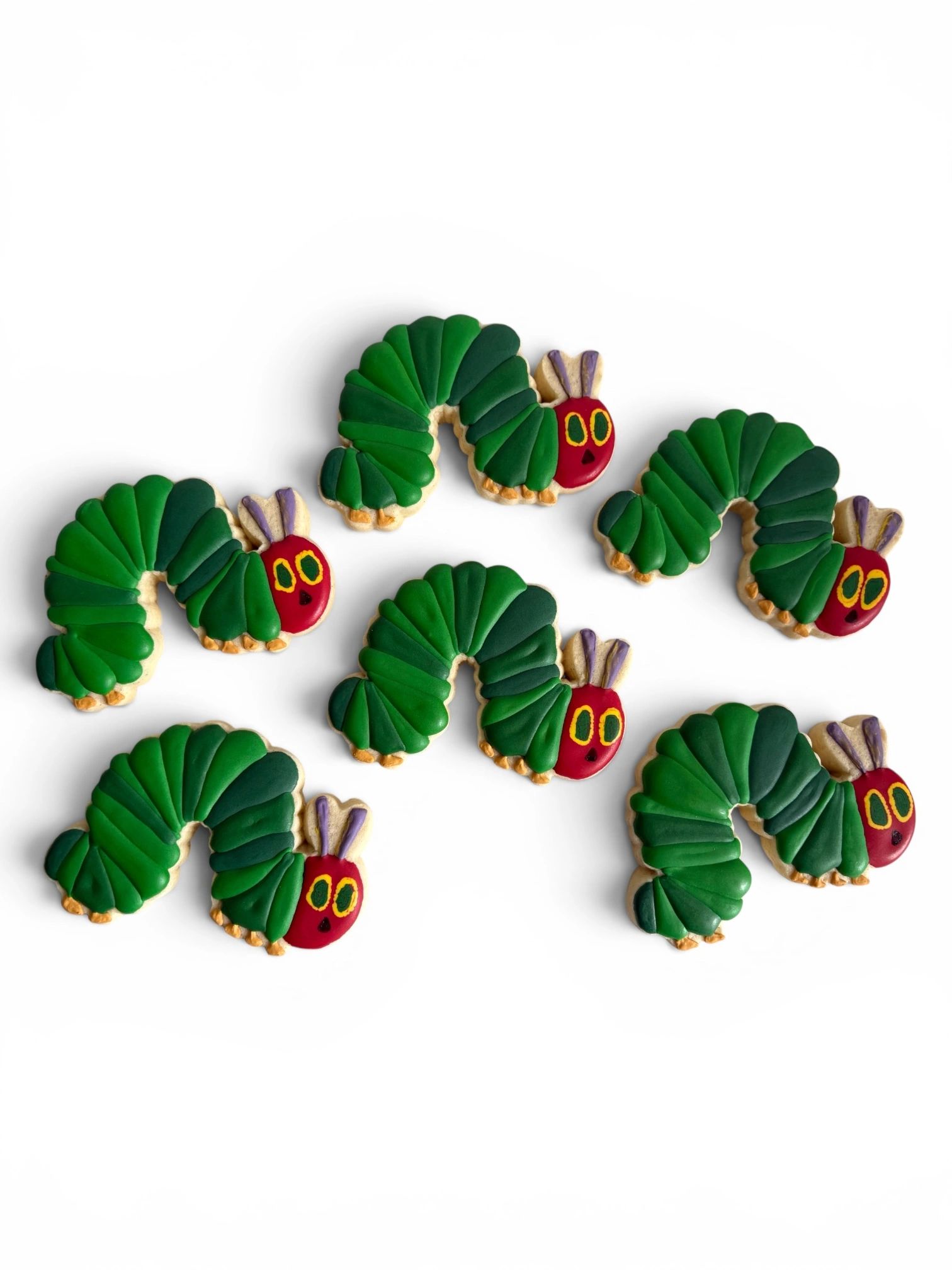 Six green caterpillar-shaped cookies with red faces.