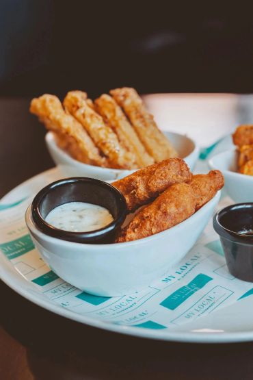 Fried appetizers with dipping sauces served in white bowls.