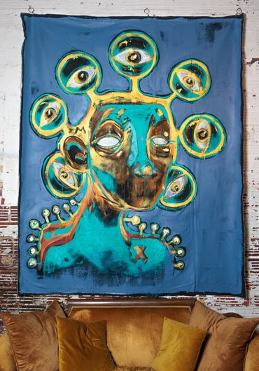 Colorful surreal painting of a figure with multiple eyes surrounding its head.
