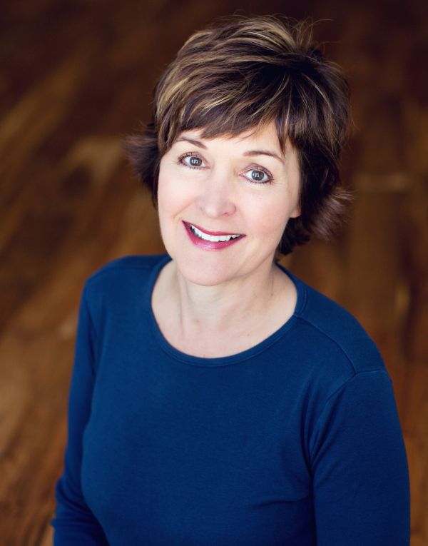 Smiling woman in blue shirt with short hair.