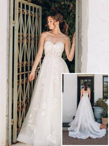 Elegant strapless white wedding dress with floral details and a flowing train.