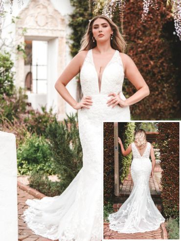 A woman modeling a white lace wedding dress outdoors.