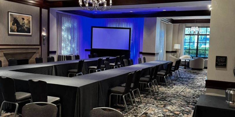 Conference room with U-shaped table setup and projector screen.