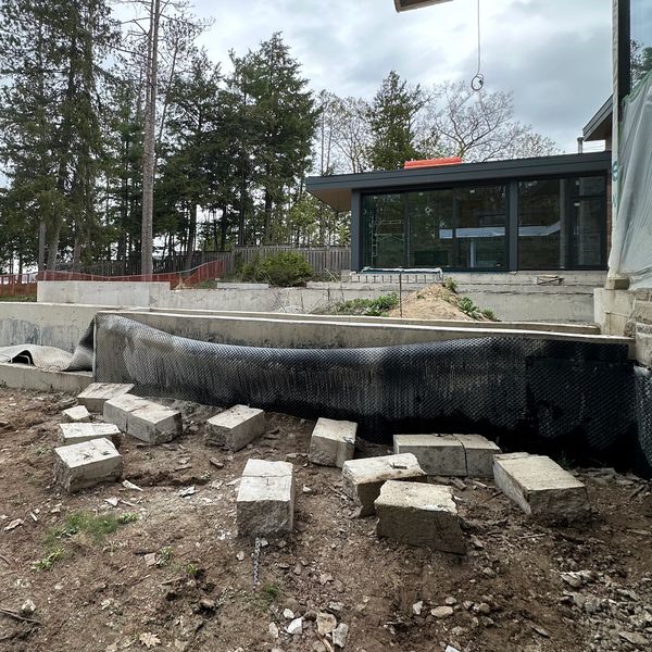 Construction site with concrete blocks and building materials near a modern house.
