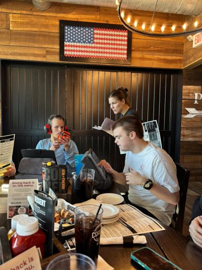 People dining and ordering at a rustic restaurant table.