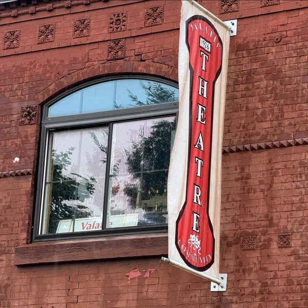 Red theatre banner on a brick building.