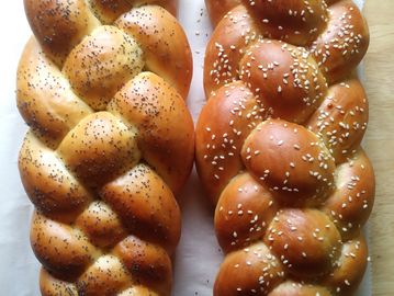 2 loaves of braided challah bread, one with sesame seeds and one with poppy seeds