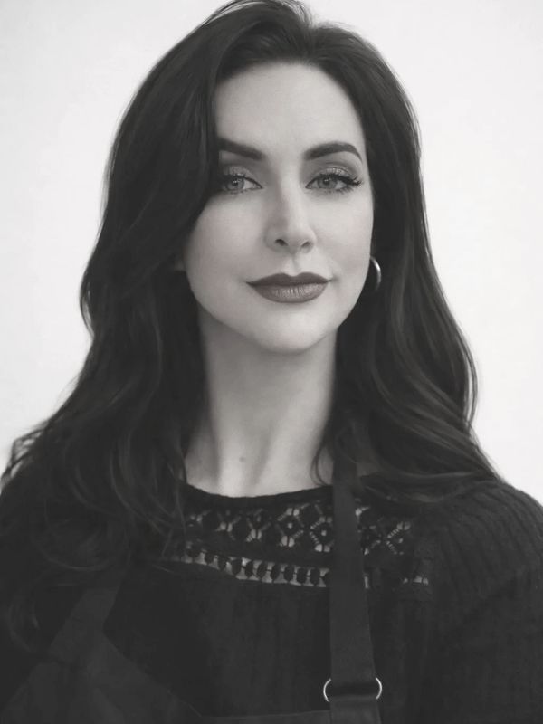 Portrait of a confident woman with dark hair and a subtle smile in black and white.