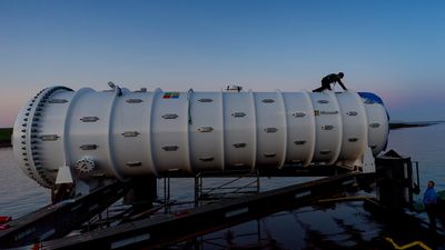 A large cylindrical device on a platform over water during dusk.