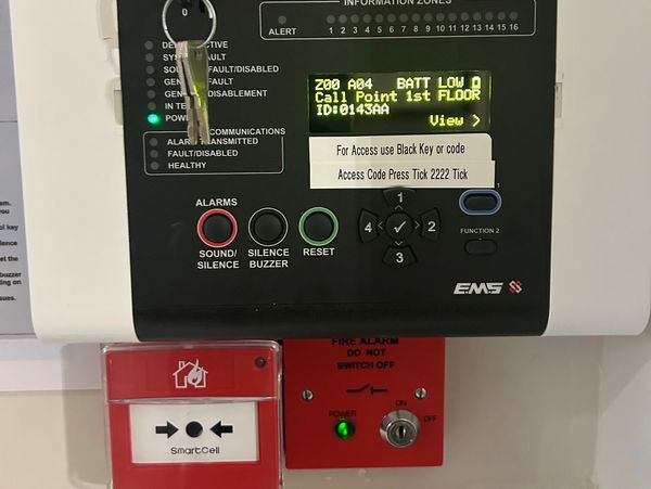 Close-up of a fire alarm control panel with instructions and status indicators.