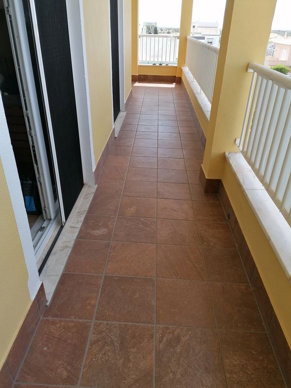 Balcony with tiled floor and yellow walls.