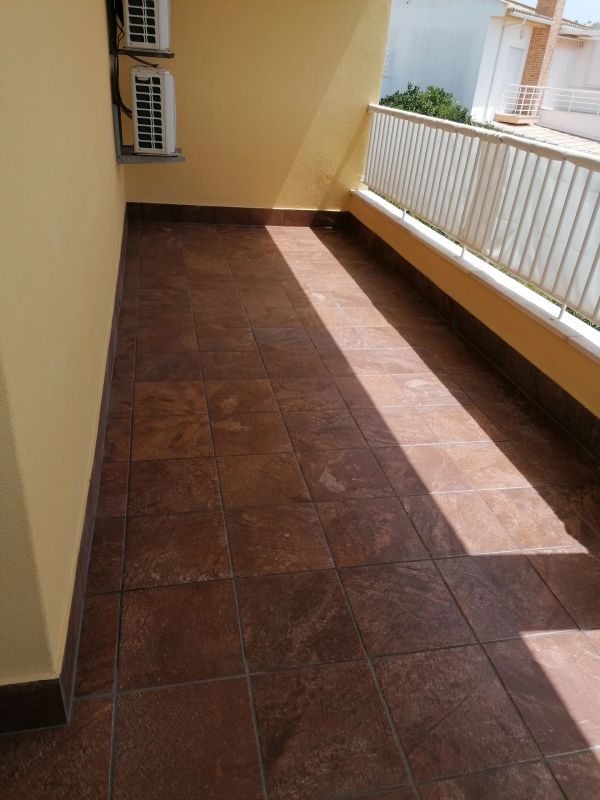 Balcony with brown tiles and yellow walls.