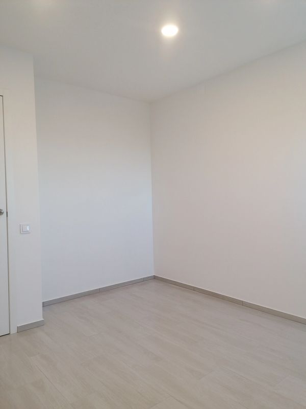 Bedroom with tiled flooring and ceiling light.