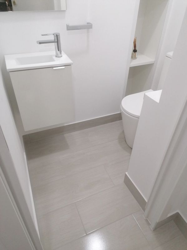 Modern minimalist white powder room with sink and toilet.