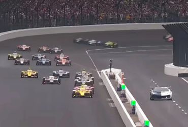 IndyCar race start with cars in formation on the track.