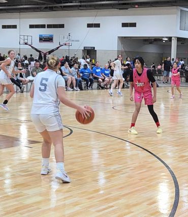 Female basketball player in white preparing to pass the ball during a game.
