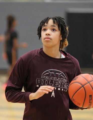 Young basketball player in maroon Pearland Oilers sweatshirt holding a basketball.