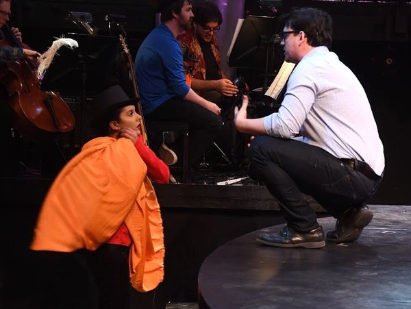 Person in theatrical costume interacting with a man on stage.