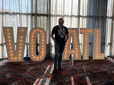 Man standing in front of illuminated VO ATL letters at a convention center.