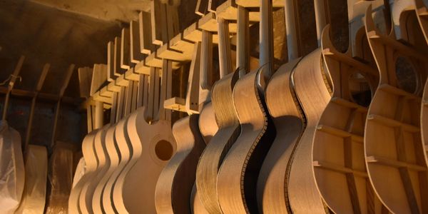 Wooden guitar bodies in various stages of construction hanging in a workshop.