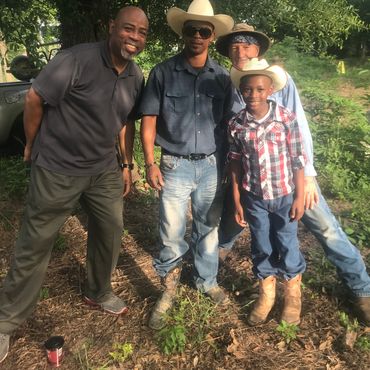 Group of four males outdoors, two wearing cowboy hats.