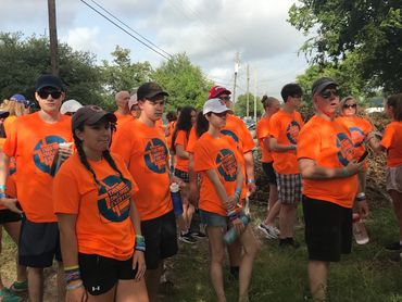 Group of people in orange shirts gathered outdoors.