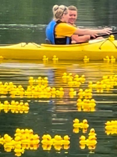 2 women in a kayak at the finish line in the river grabbing the winning Dexter Duck Derby winners