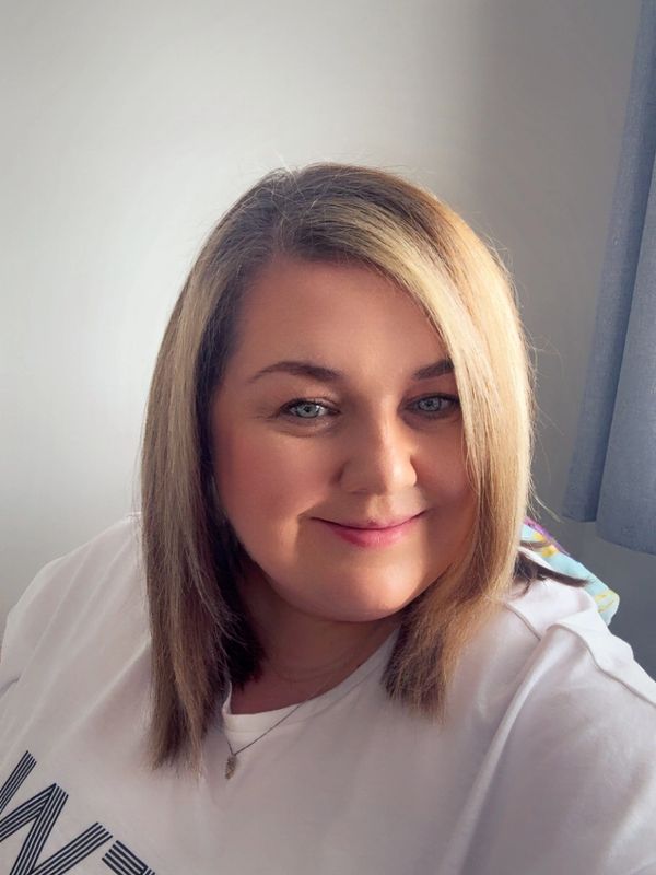 A smiling woman with blonde hair wearing a white shirt.
