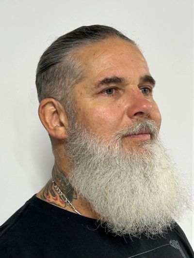 Profile of a man with a long white beard and slicked-back hair.