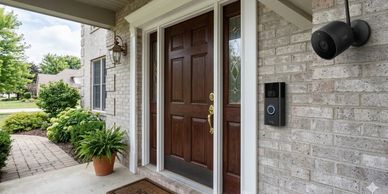 Front porch with a wooden door, security camera, and doorbell.