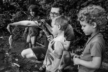 dad holds up fish while toddlers look on-documentary photography