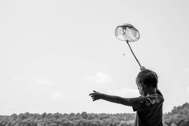 toddler fishes with broken net black and wet documentary photograph