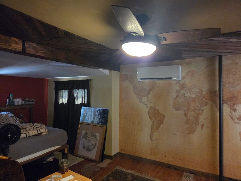 Cozy room with a wooden ceiling fan and vintage world map wallpaper.