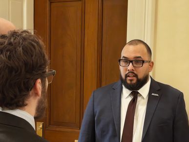 Two men in suits discussing a policy document indoors.