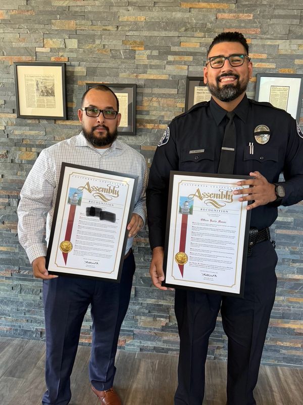 Two men holding framed California Assembly recognition certificates.