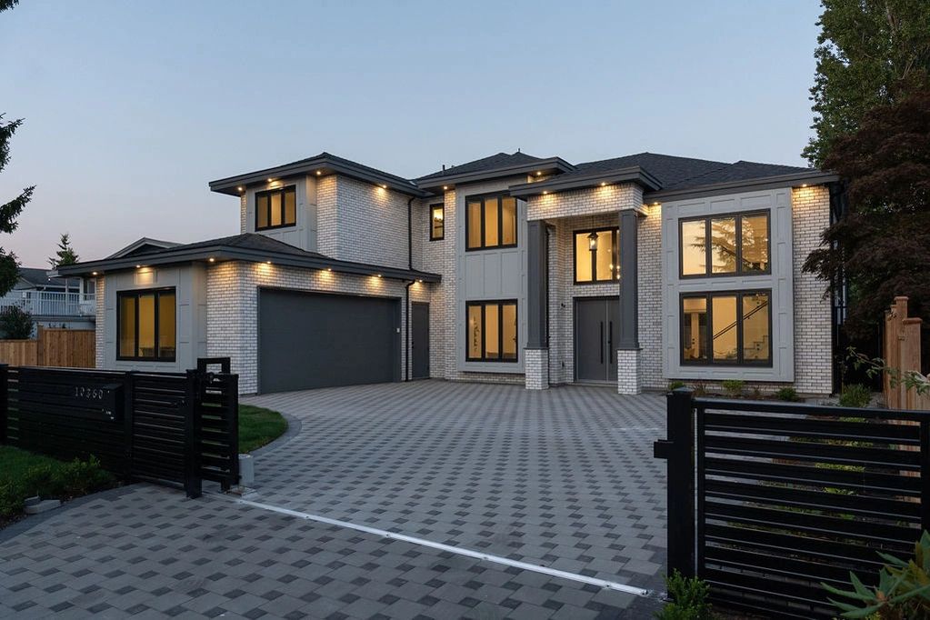 Modern two-story house with illuminated exterior and spacious driveway.