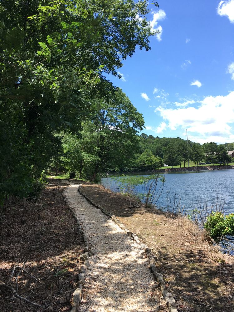 Picture of a lake with trees and a pebbled path 