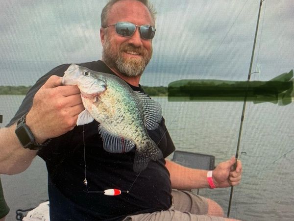 Man holding a large fish while fishing on a lake.
