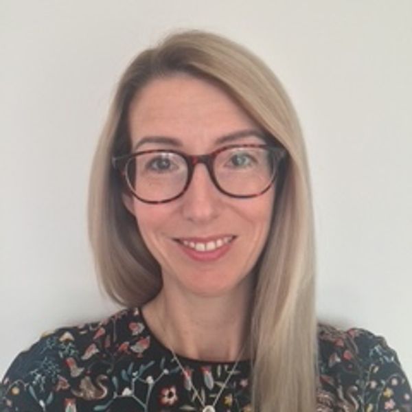 Smiling woman with glasses and long blonde hair.