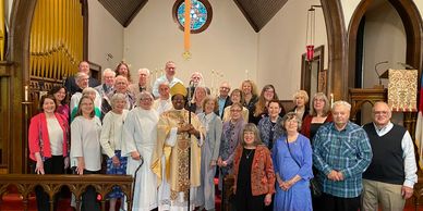 A diverse church group posing inside a chapel with a bishop in ceremonial robes.