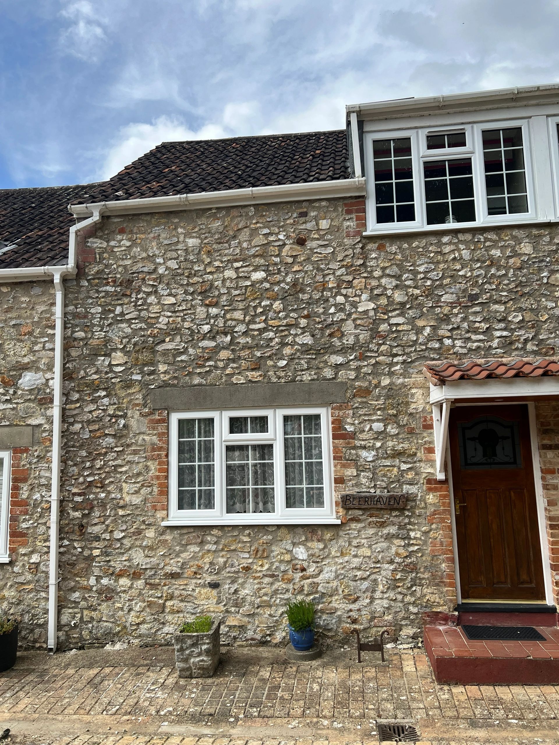 Stone house with white windows and a wooden door.