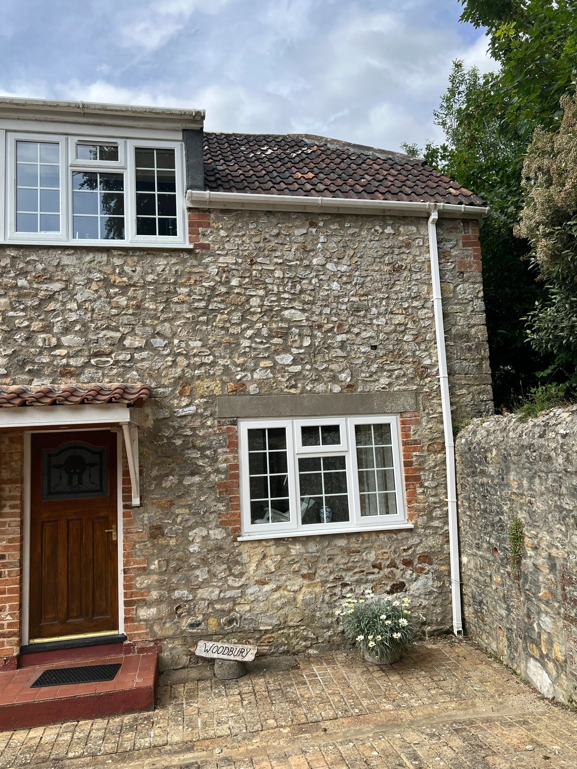 Stone house with a brown door and white windows.
