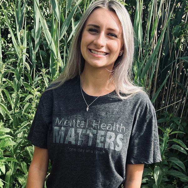 Smiling woman wearing a mental health awareness shirt.
