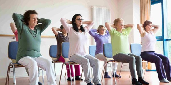 Group of elderly women exercising while seated.